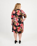Woman wearing a black floral dress on a white background. This dress is the Appleton Wrap Dress sewing pattern from Cashmerette.