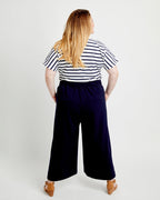 Person wearing a striped shirt and wide-leg pants on a white background. These pants are the Calder Pants & Shorts sewing pattern from Cashmerette.