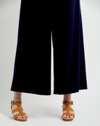 Person wearing navy blue pants and brown sandals on a white background. These pants are the Calder Pants & Shorts sewing pattern from Cashmerette.