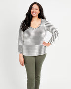 A woman standing, wearing a striped long-sleeved t-shirt and green pants. This t-shirt is the Concord T-Shirt sewing pattern from Cashmerette.