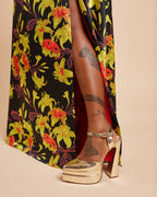 Gold high-heeled shoes with a colorful floral-patterned skirt on a beige background. This dress is the Ellington Strapless Dress sewing pattern from Cashmerette.