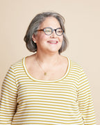 Woman wearing a yellow and white striped shirt against a beige background. This is the Grafton Dress, Top & Skirt sewing pattern from Cashmerette.