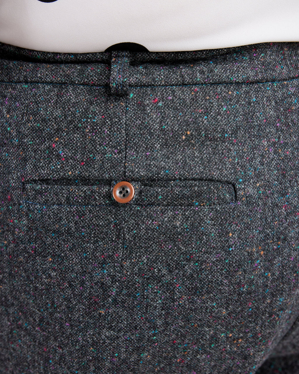 Close-up of a gray textured fabric with a button on a white background. These pants are the Meriam Trousers sewing pattern from Cashmerette.