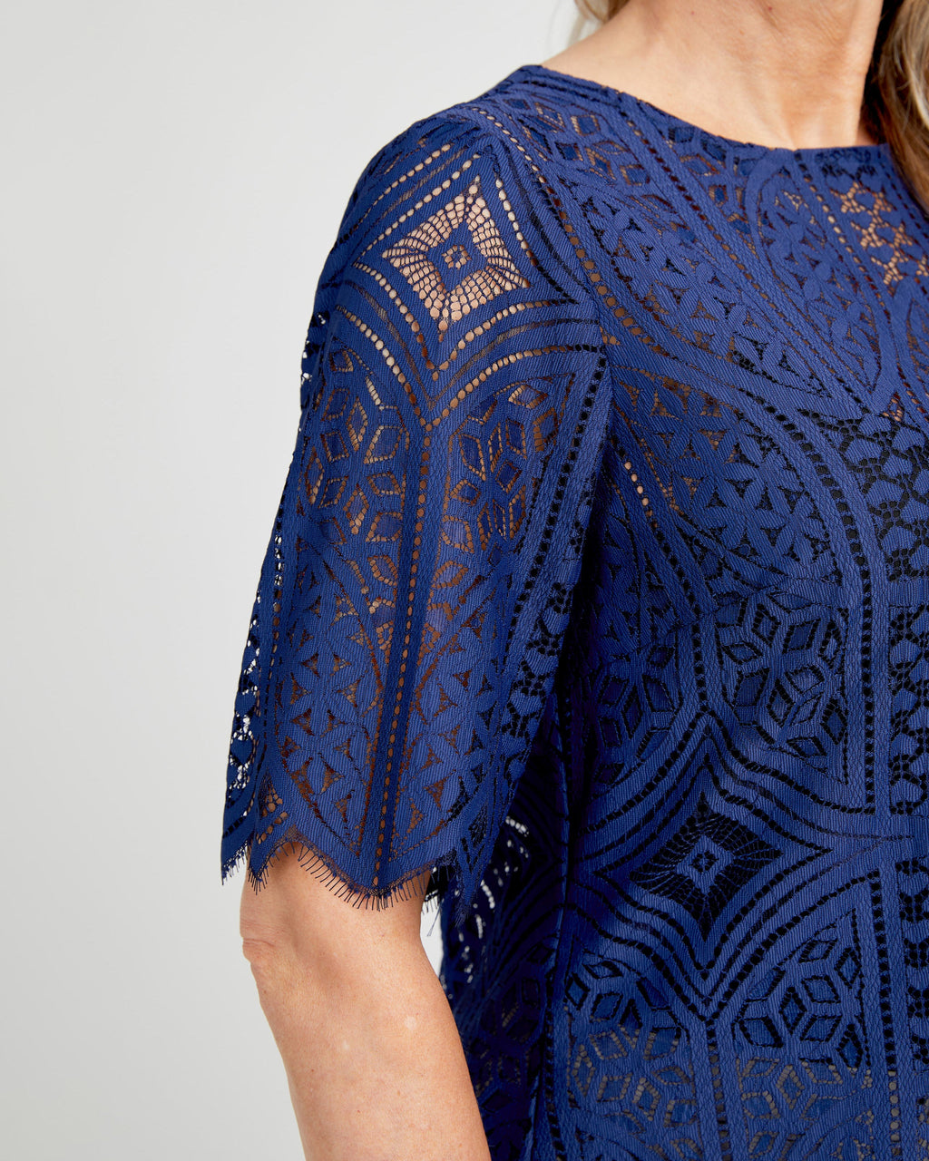 Navy blue lace dress with geometric pattern on a plain background. This top is the Montrose Top sewing pattern from Cashmerette.