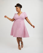 Woman wearing a pink dress on a white background. This dress is the Roseclair Wrap Dress sewing pattern from Cashmerette.