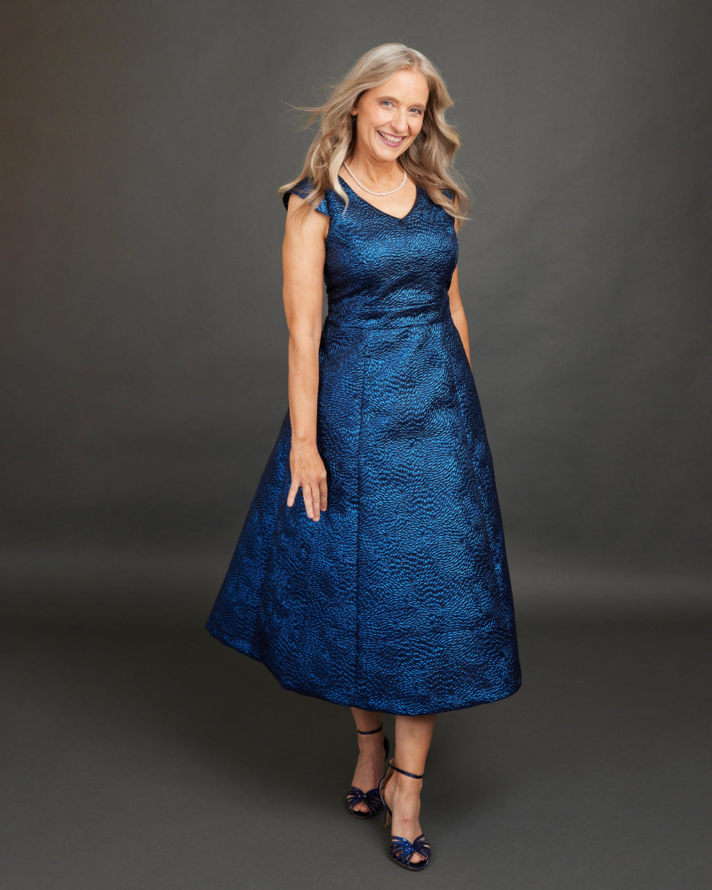 Woman wearing a blue dress against a gray background. This dress is the Upton Dress & Skirt sewing pattern from Cashmerette.